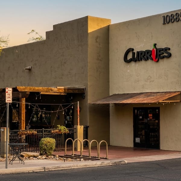 Exterior of Curries restaurant with a patio, bike rack, and blue awning under a clear sky.